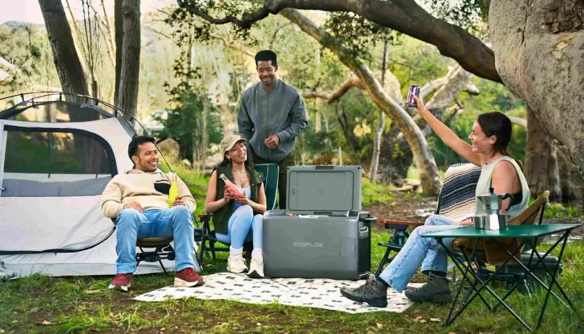 Amis profitant d'un emplacement camping-car chez particulier, avec tente, glacière et boissons.