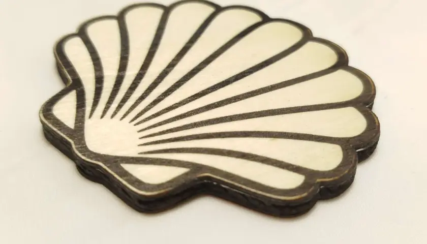 Coquille de bois stylisée, rappelant la coquille Compostelle, avec des lignes noires sur fond clair.