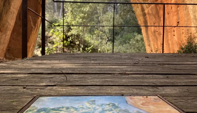 Sur le plateau de Bibemus, un tableau posé sur un pont de bois offre une vue sur la nature environnante, dominée par des falaises ocres.