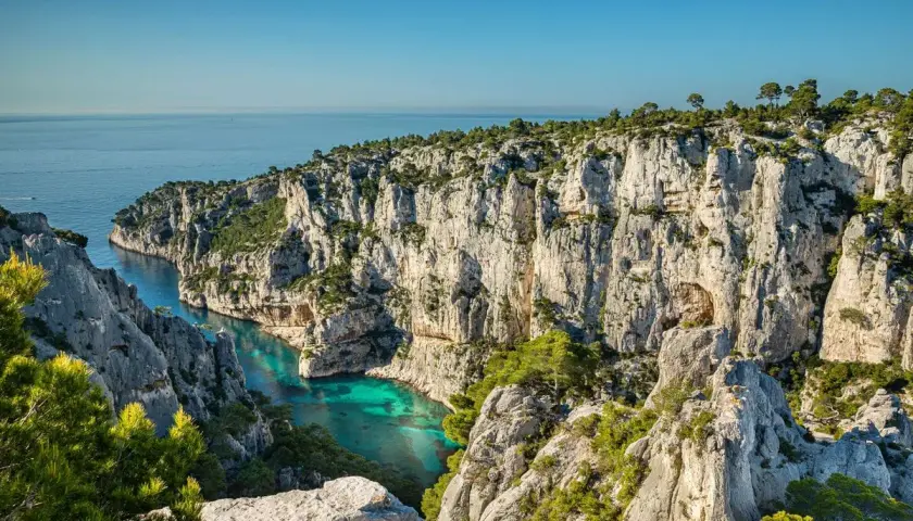 Vue spectaculaire depuis le belvédère d'En Vau sur la calanque aux eaux turquoise, entourée de falaises calcaires et de pins.