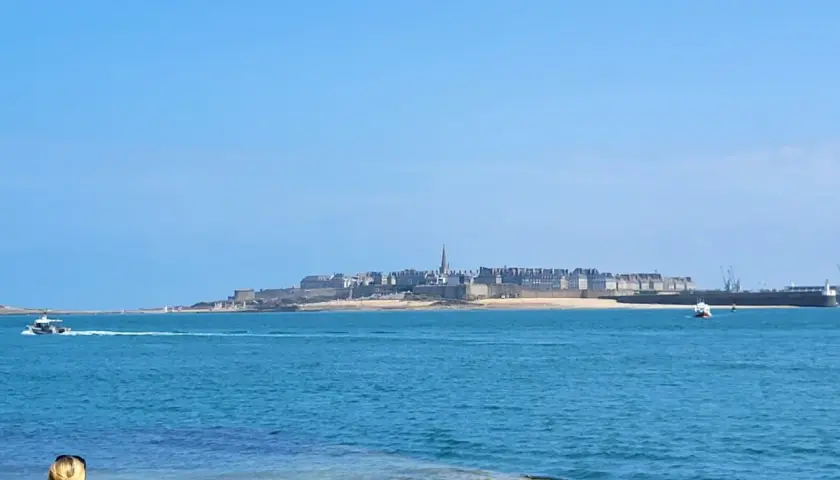 Une personne admire la vue sur la ville fortifiée, une belle journée pour une randonnée le long de la Rance.