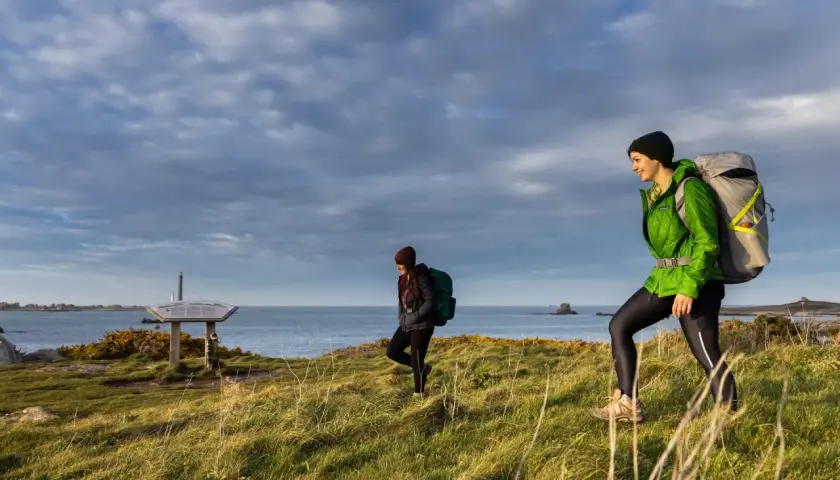 Deux randonneuses explorent le littoral breton, profitant d'une belle journée pour leur randonnée les abers Bretagne. Le ciel est couvert, mais la lumière est douce.