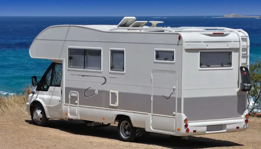 Camping-car blanc stationné sur une aire de camping-car à Bormes-les-Mimosas, face à la mer Méditerranée.