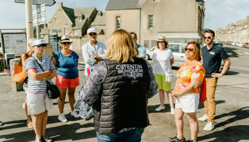 Un groupe de touristes écoute attentivement une guide dans le Val de Saire, un lieu unique par nature.