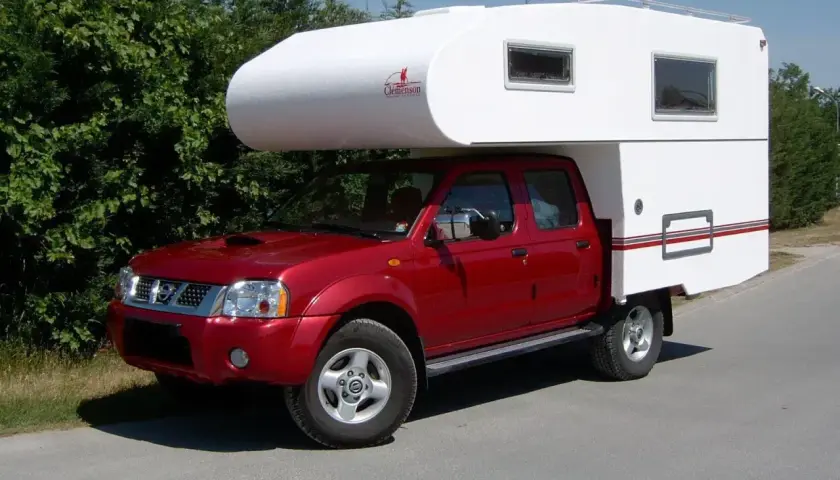 Un camping-car increvable rouge, prêt pour l'aventure. Sa cabine blanche offre un espace de vie confortable pour explorer le monde.