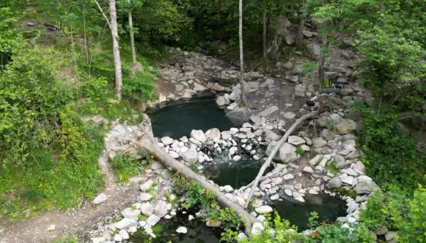 Baignades naturelles dans la forêt, près de Merens-les-Vals. Un sac à dos est posé sur un tronc d'arbre.