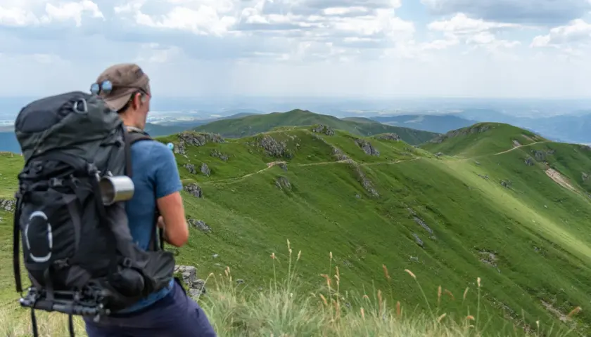 Randonnée Cantal 2 jours : un randonneur admire le paysage verdoyant des monts du Cantal, prêt pour son aventure.