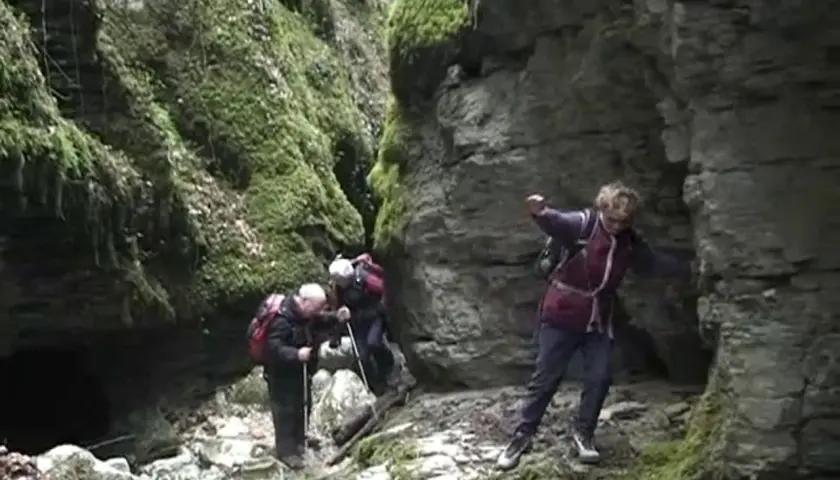 Trois randonneurs explorent le canyon des Gueulards, un passage étroit et rocheux couvert de mousse.