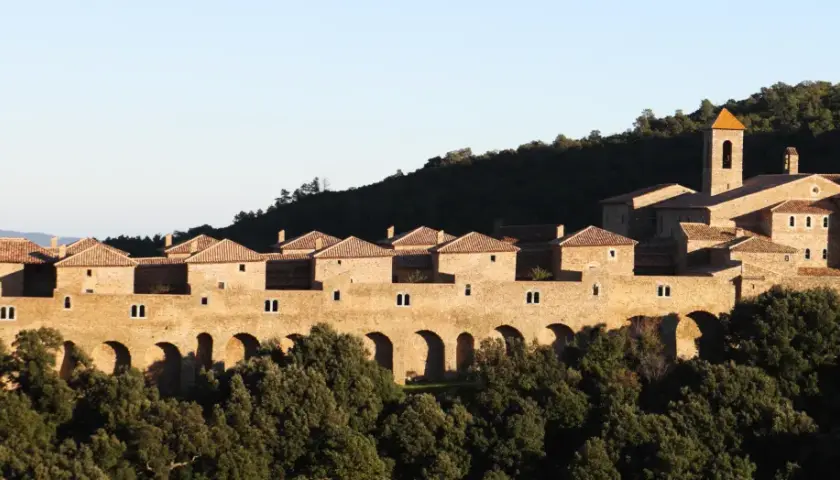 Vue d'une chartreuse en pierre, perchée sur une colline boisée, parfaite pour une randonnée Chartreuse de la Verne.