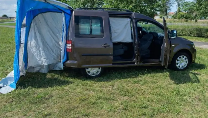 Un caddy tramper aménagé avec une tente latérale bleue et grise, prêt pour l'aventure en plein air.