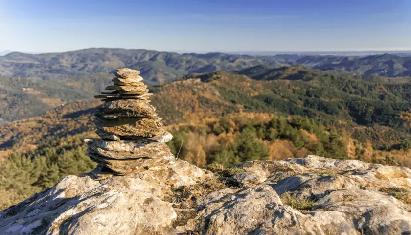Un cairn marque le chemin de Stevenson, offrant une vue imprenable sur les collines automnales. Chaque étape est une découverte.