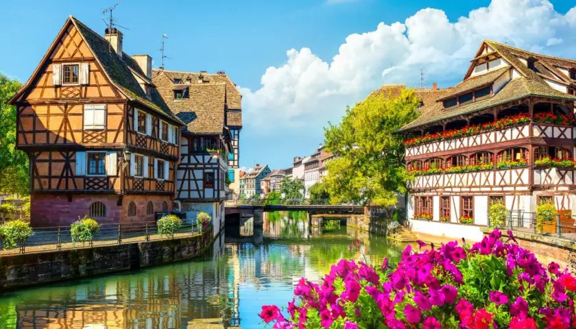 La Petite France à Strasbourg, un joyau pour l'alsace tourisme. Maisons à colombages pittoresques au bord de l'eau, reflets dans le canal, fleurs éclatantes.