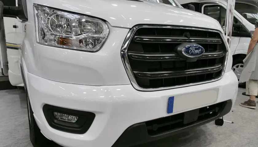 Avant d'un camping-car blanc avec le logo Ford. Ce véhicule est équipé d'un moteur Ford 2.2 TDCI, parfait pour vos voyages.