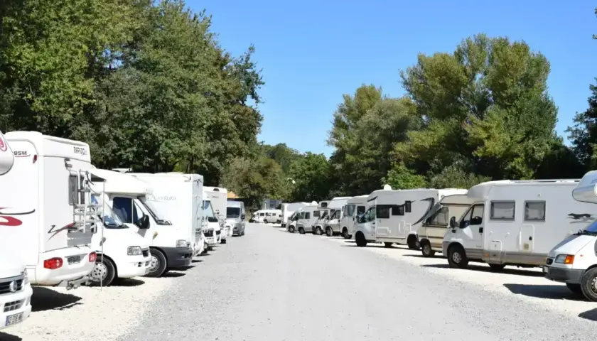 Grand parking de camping-cars près du zoo de Beauval, sous un ciel bleu et des arbres verdoyants.