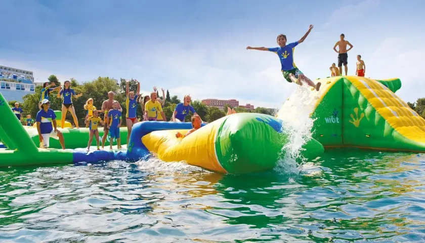 Des enfants s'amusent dans un aquapark gonflable près de Paris, un garçon saute dans l'eau.