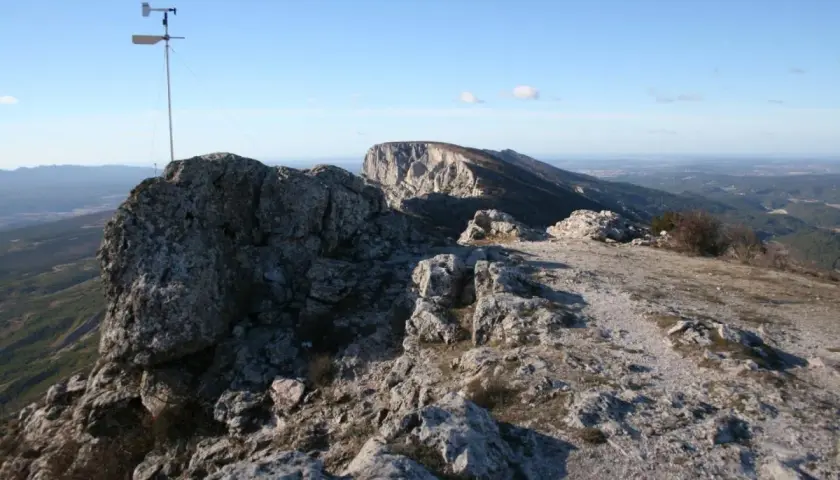 Sommet rocheux avec un anémomètre, offrant une vue panoramique sur la vallée. Le pic des mouches altitude est un lieu idéal pour observer le vent.