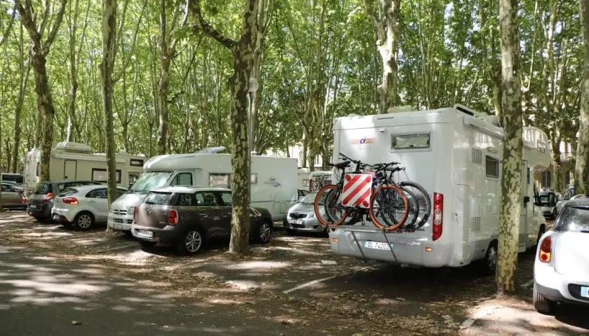 Stationnement gratuit pour camping-cars à Bordeaux, sous les arbres. Des vélos sont prêts pour explorer la ville.
