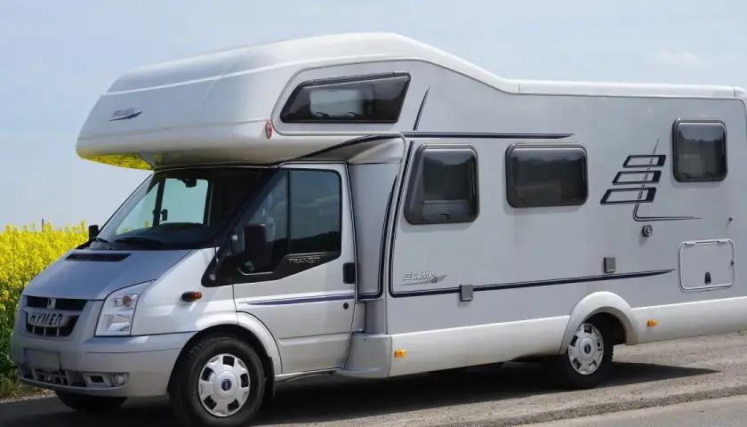 Camping car Hymer sur le bord du canal de Nantes à Brest, au milieu d'un champ de colza en fleurs.