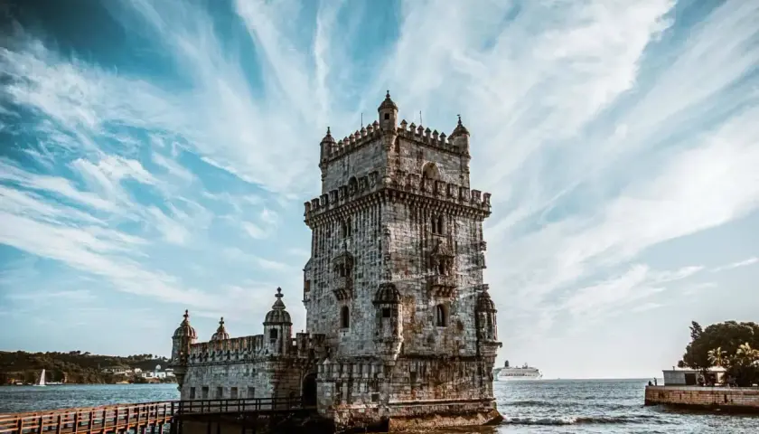 La Tour de Belém, un incontournable pour savoir que faire à Lisbonne, se dresse fièrement sur l'eau sous un ciel spectaculaire.