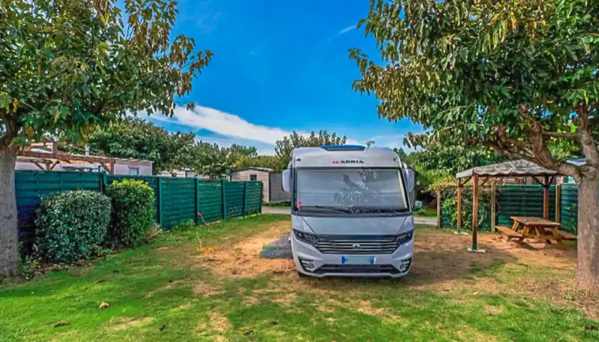 Un camping-car Adria prêt pour l'aventure sur l'Île d'Oléron. Un coin paisible avec pelouse et abri pique-nique.