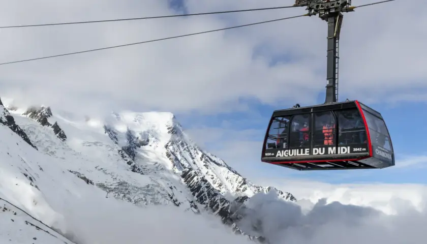 La télécabine de l'Aiguille du Midi survole un paysage alpin spectaculaire, transportant des passagers vers les sommets enneigés.