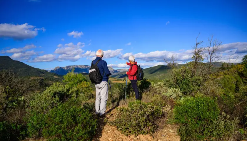 Un couple profite d'un week-end randonnée en amoureux, admirant le paysage montagneux sous un ciel bleu éclatant.