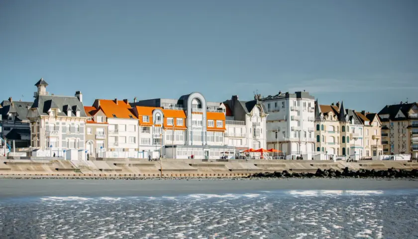 Bâtiments colorés bordant la plage sur la Côte d'Opale, avec des toits orange vif et des façades blanches et grises.