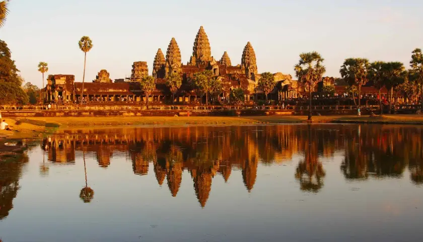 Angkor Wat au coucher du soleil, un incontournable pour savoir que faire au Cambodge. Les tours se reflètent dans l'eau.