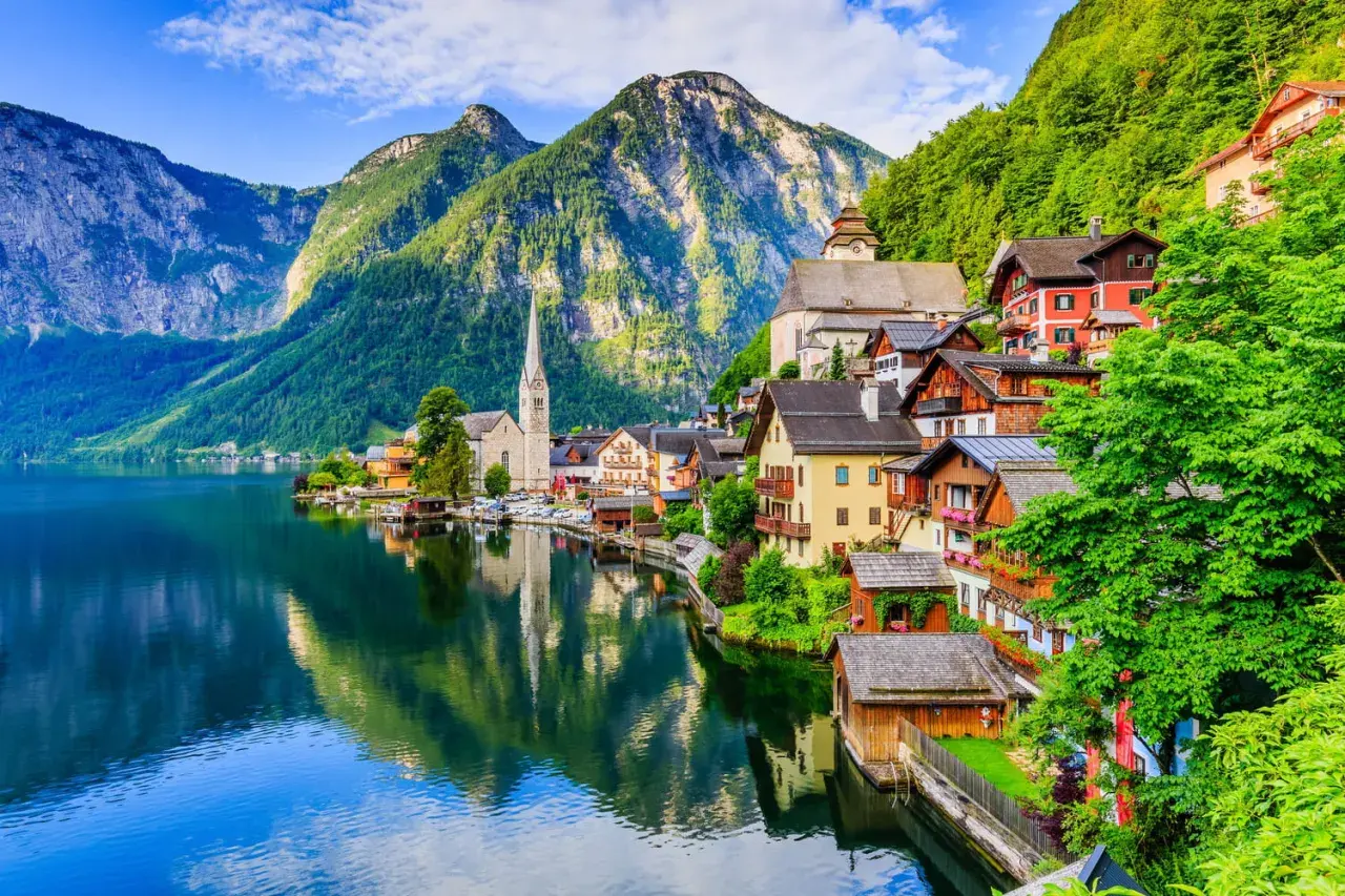 Village pittoresque au bord d'un lac, montagnes verdoyantes en arrière-plan. Idéal pour savoir que faire en Autriche.