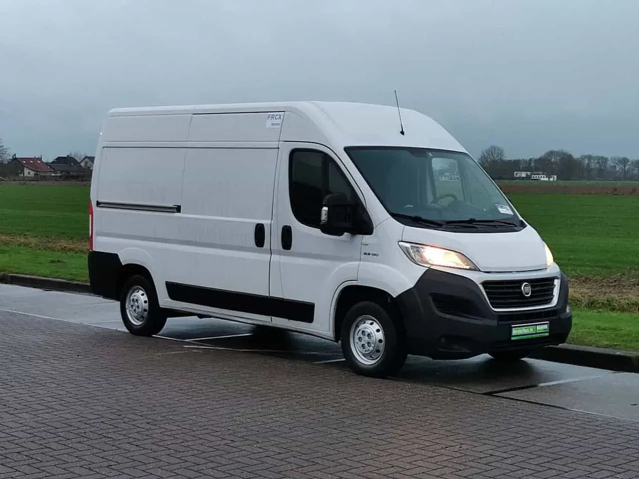 Un fourgon blanc Fiat Ducato 2.3 Multijet 150, symbole de fiabilité, stationné sur un pavé.