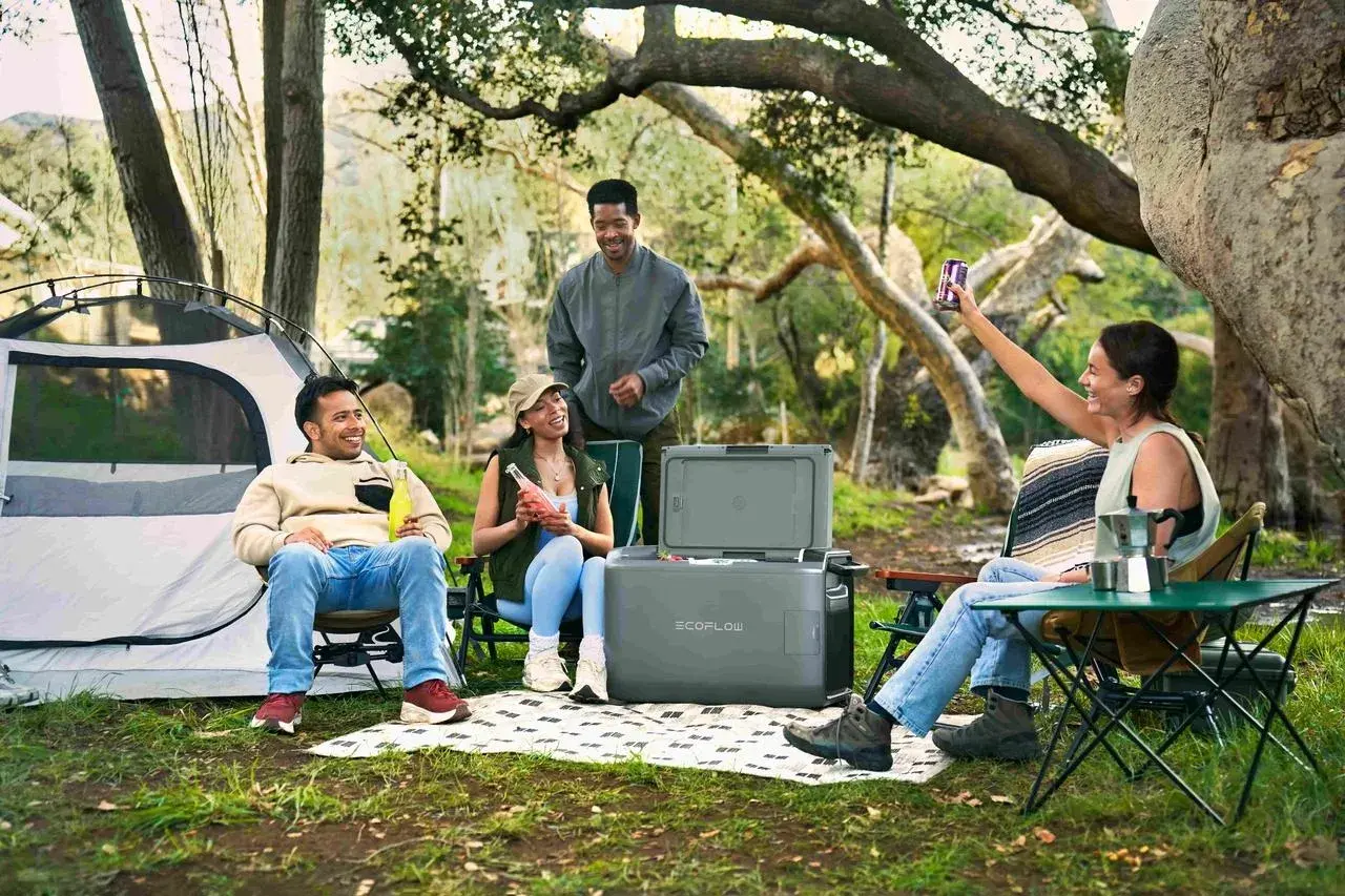 Amis profitant d'un emplacement camping-car chez particulier, avec tente, glacière et boissons.