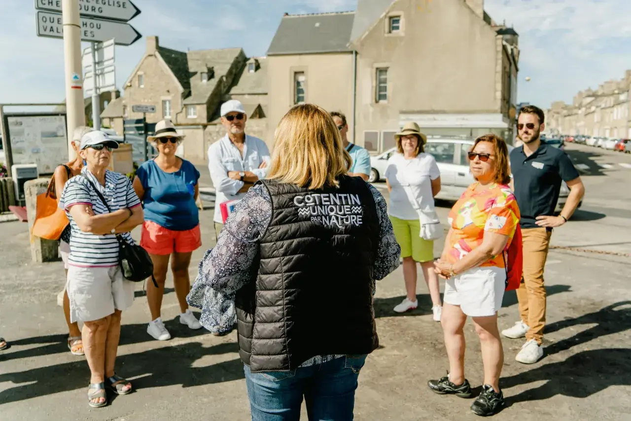 Un groupe de touristes écoute attentivement une guide dans le Val de Saire, un lieu unique par nature.