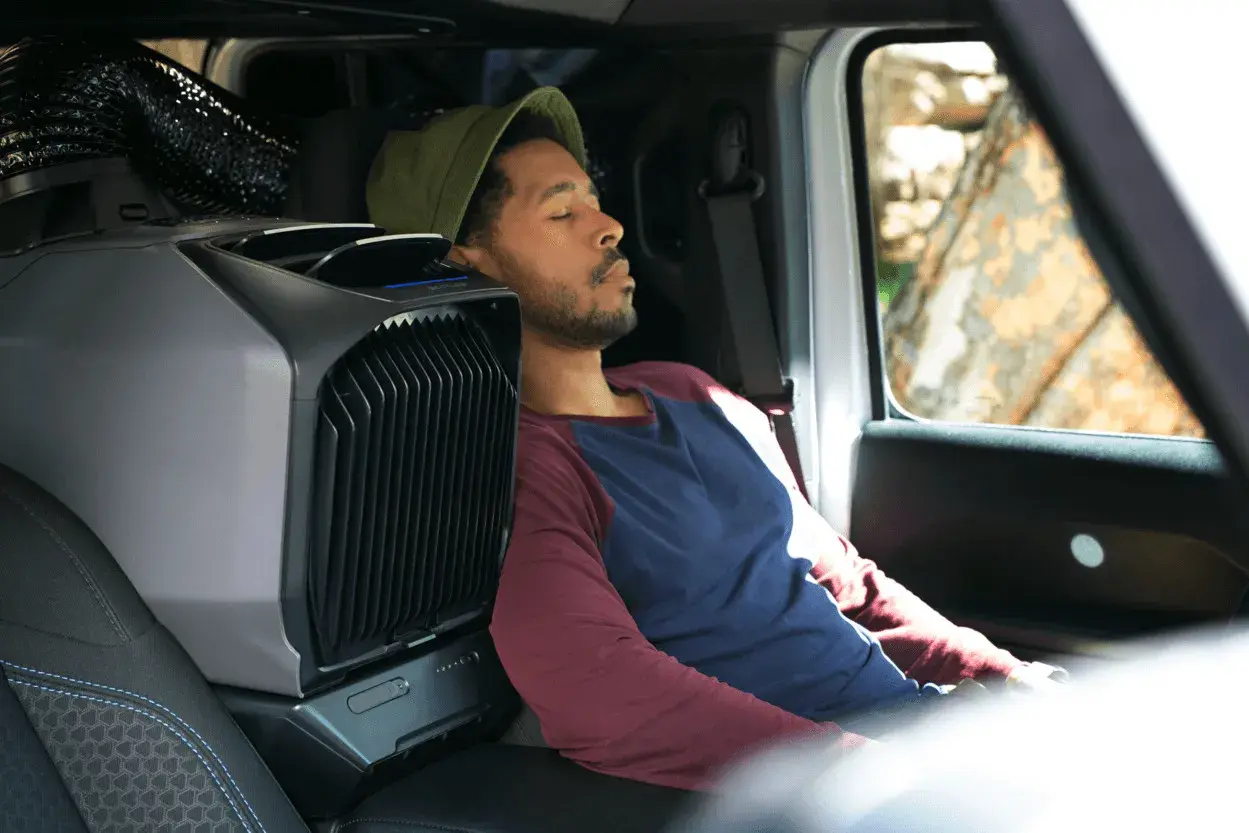 Un homme dort paisiblement dans son camping-car, grâce à un climatiseur portable. L'idéal pour une aire de camping-car gratuit avec électricité.