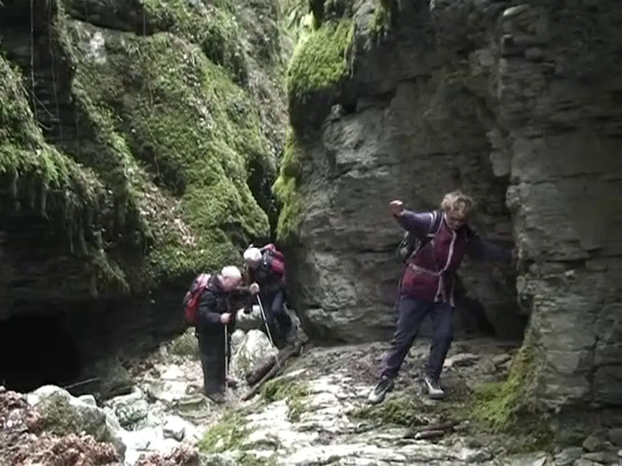 Trois randonneurs explorent le canyon des Gueulards, un passage étroit et rocheux couvert de mousse.
