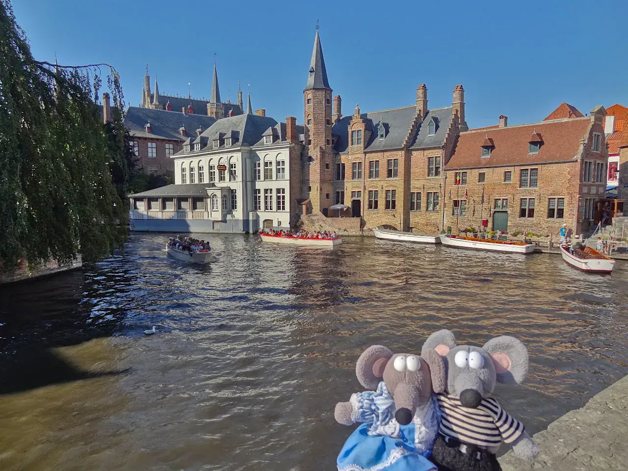 Deux peluches souris profitent d'une balade en bateau sur les canaux de Bruges, une excellente idée pour savoir que faire à Bruges.