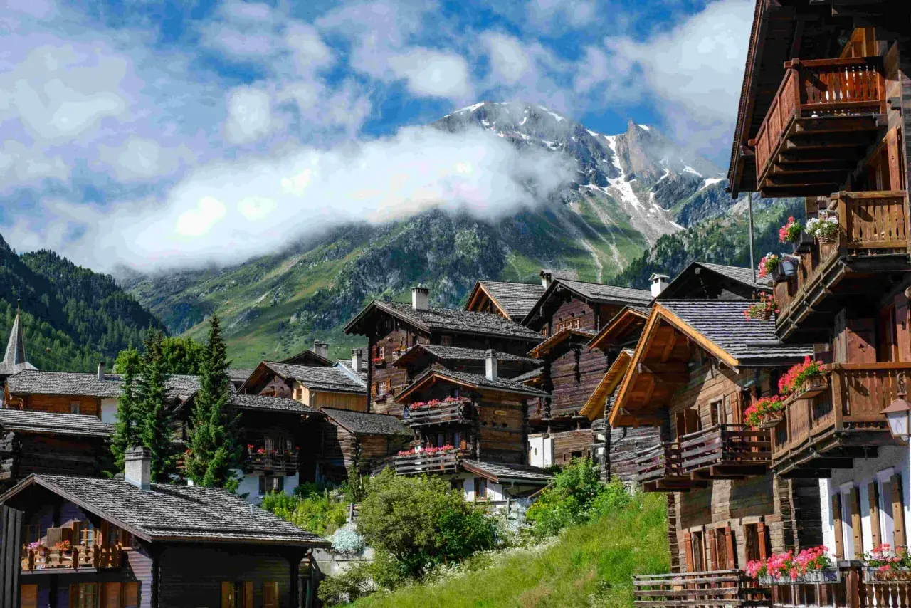 Villages de chalets en bois fleuris, montagnes enneigées en arrière-plan. Une belle idée de que faire en Suisse pour un séjour pittoresque.
