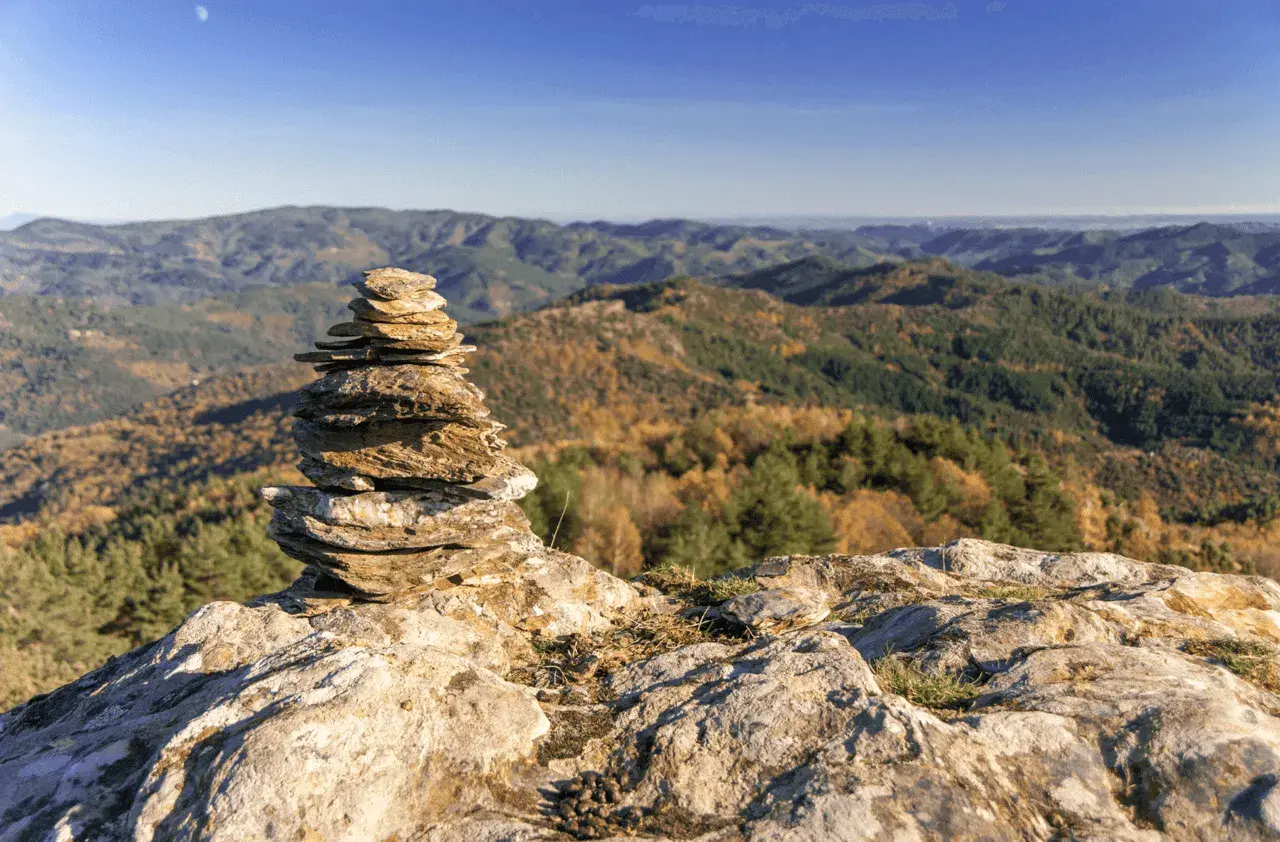 Un cairn marque le chemin de Stevenson, offrant une vue imprenable sur les collines automnales. Chaque étape est une découverte.