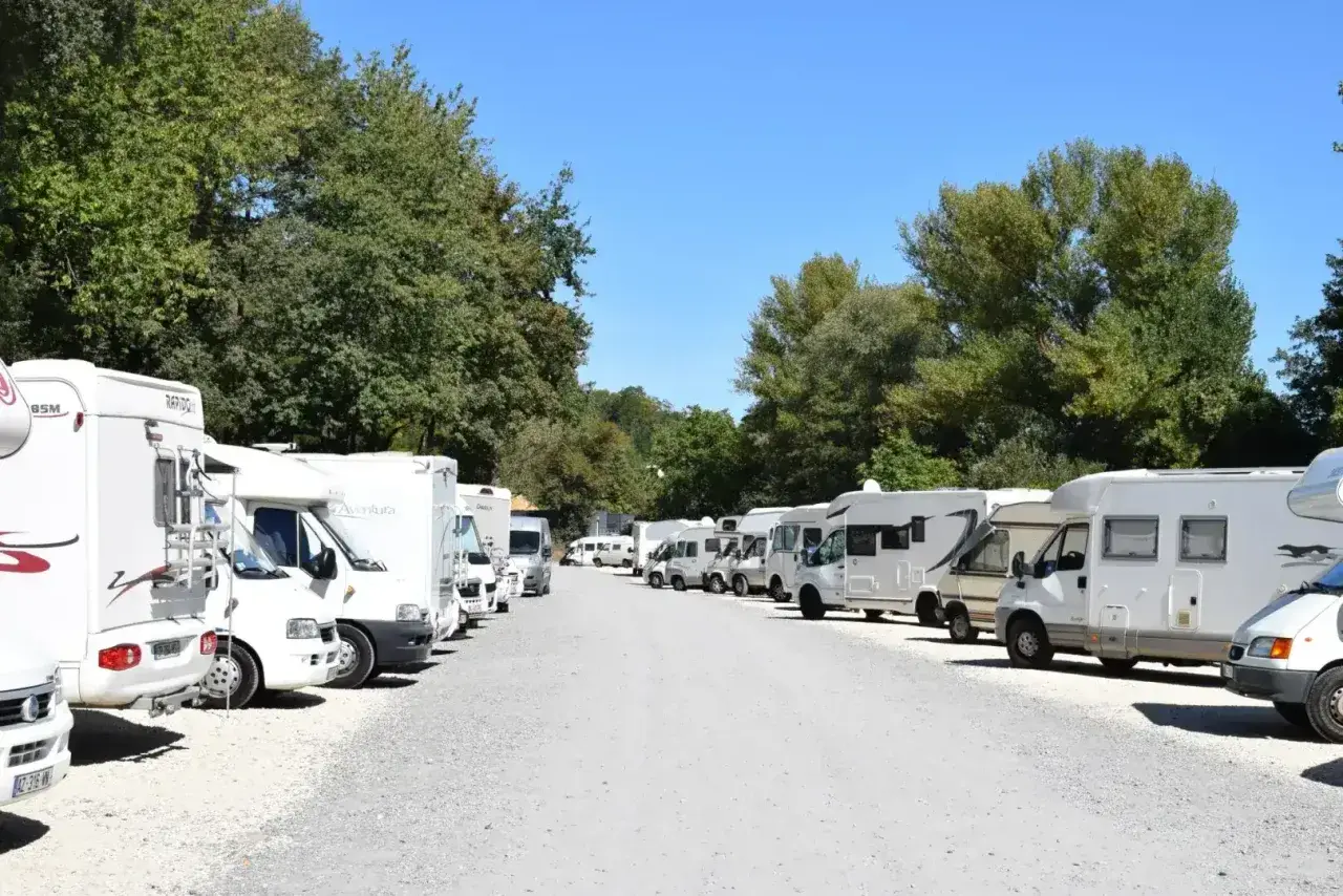 Grand parking de camping-cars près du zoo de Beauval, sous un ciel bleu et des arbres verdoyants.