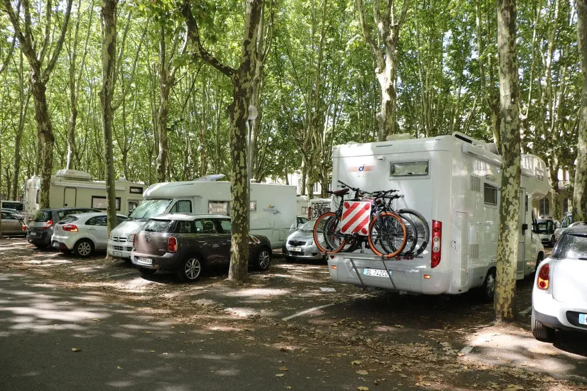 Stationnement gratuit pour camping-cars à Bordeaux, sous les arbres. Des vélos sont prêts pour explorer la ville.