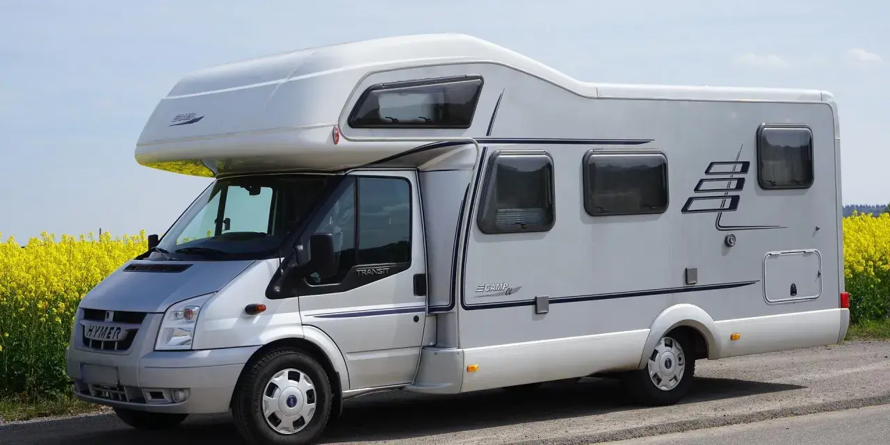 Camping car Hymer sur le bord du canal de Nantes à Brest, au milieu d'un champ de colza en fleurs.