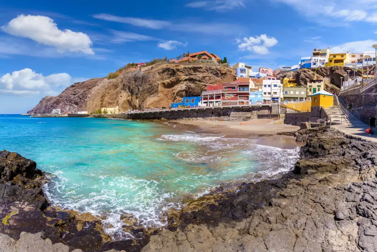 Plage de sable, maisons colorées accrochées à flanc de falaise, eaux turquoise. Idéal pour savoir que faire aux Canaries.