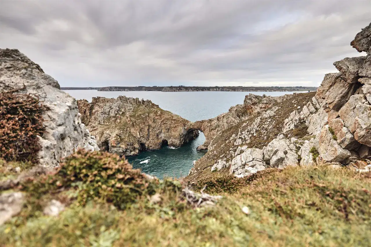 Vue spectaculaire de la pointe de Dinan, avec son arche rocheuse naturelle et la mer agitée.
