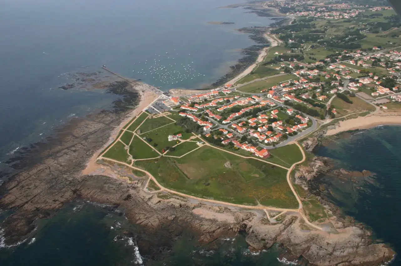 Vue aérienne de la pointe Saint-Gildas, avec ses maisons aux toits rouges, son port et ses rochers battus par la mer.