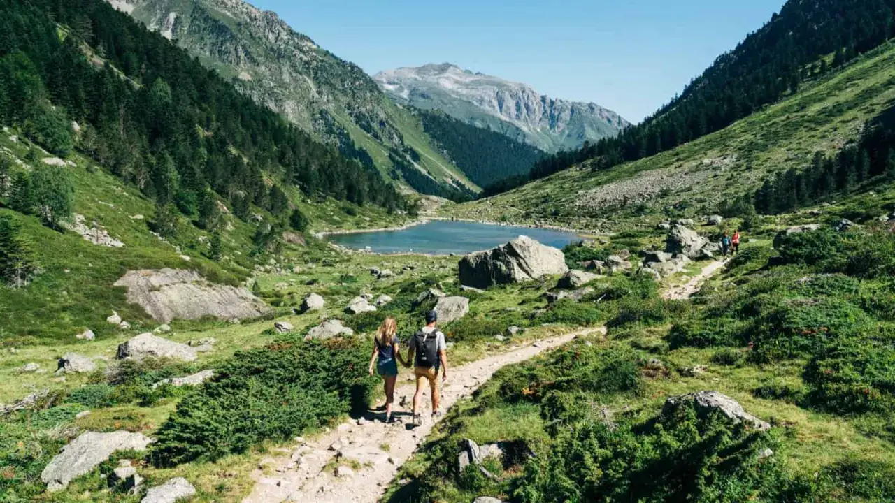 Couple en randonnée dans le Val d'Azun, profitant d'un lac de montagne entouré de verdure et de sommets.