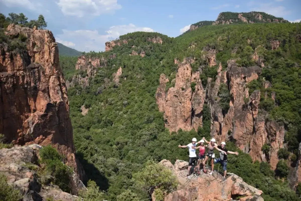 Quatre amis en tenue d'aventure profitent de la vue spectaculaire sur la gorge du Blavet, entourés de falaises rocheuses et de végétation luxuriante.
