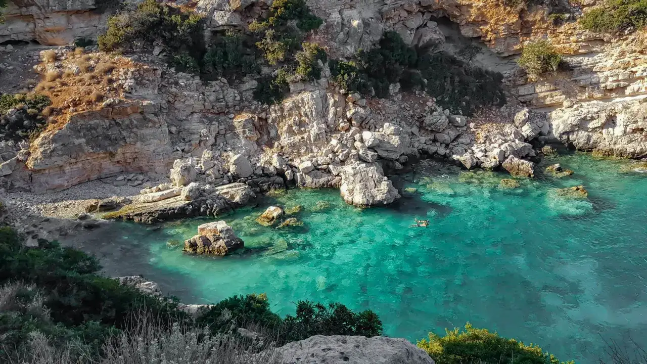 Plongeurs profitant du snorkeling en Crète dans une crique aux eaux turquoise, entourée de falaises rocheuses et de végétation méditerranéenne.