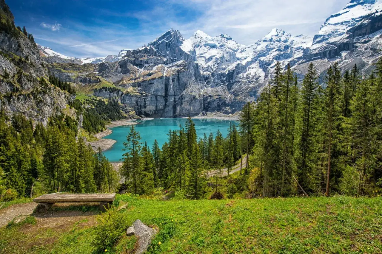 Un banc en bois invite à admirer le lac turquoise et les montagnes enneigées. Idéal pour savoir que faire en Suisse.