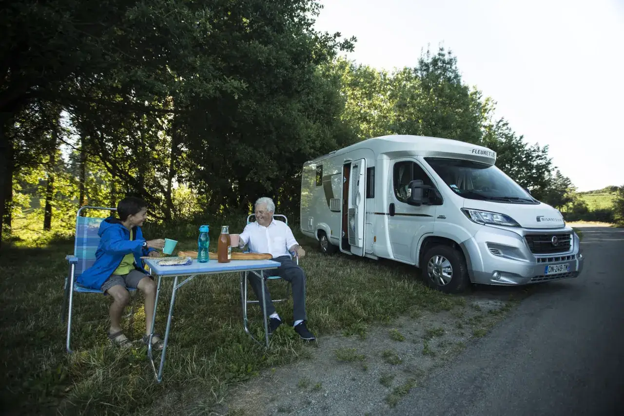 Un grand-père et son petit-fils profitent d'un pique-nique près de leur camping-car, le long du canal de Nantes à Brest.