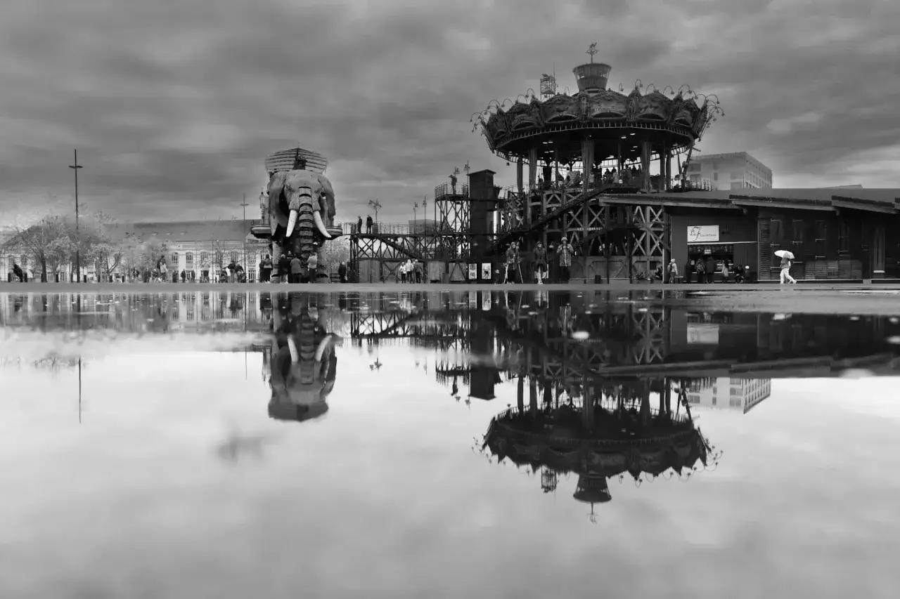 Nantes : activités à découvrir. L'éléphant mécanique et le carrousel des mondes marins se reflètent dans les flaques d'eau, créant une scène surréaliste.