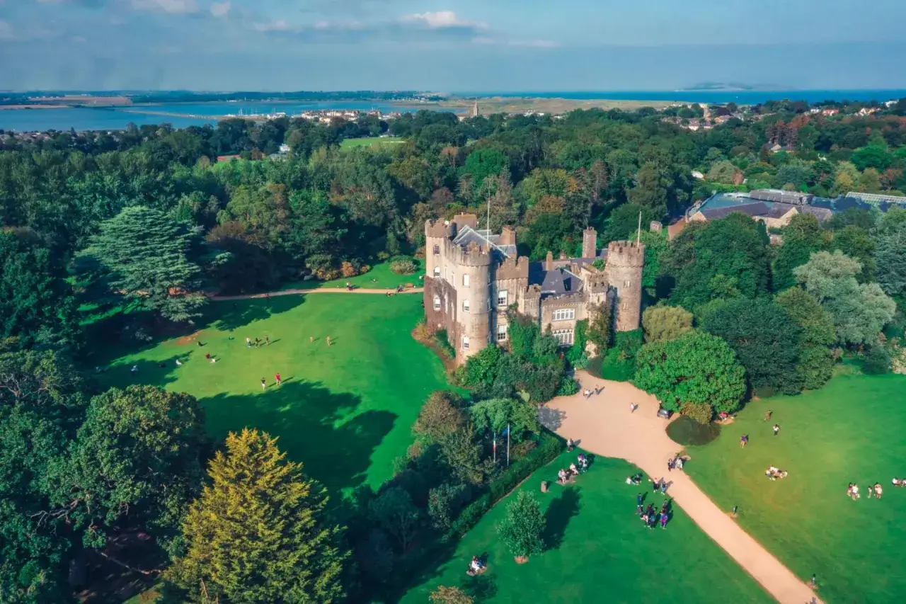 Un ch&acirc;teau m&eacute;di&eacute;val entour&eacute; de verdure, id&eacute;al pour savoir que faire &agrave; Dublin. Des visiteurs profitent du soleil sur la pelouse.